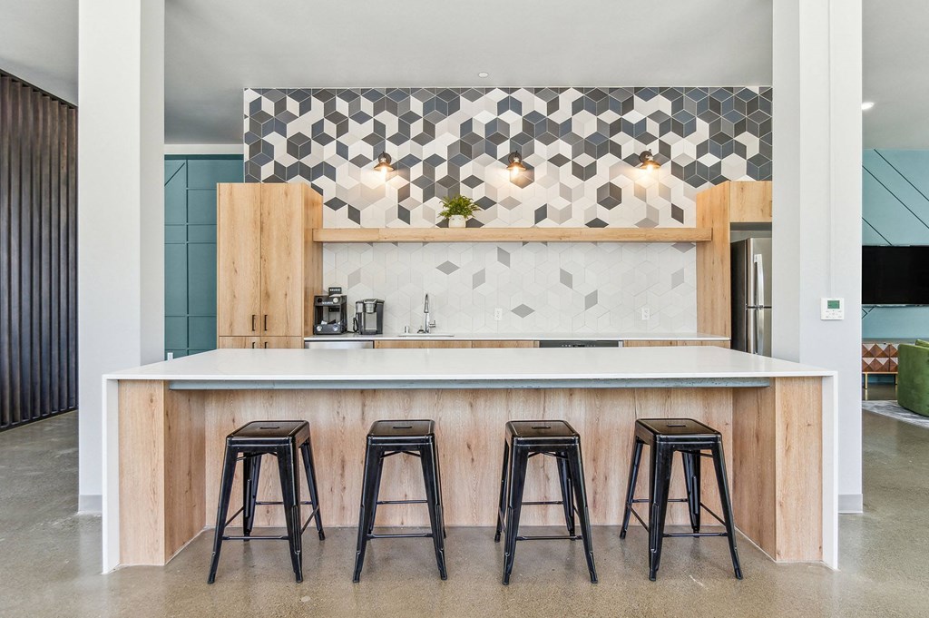 a kitchen with a white counter top and three black and white stools in front of it
