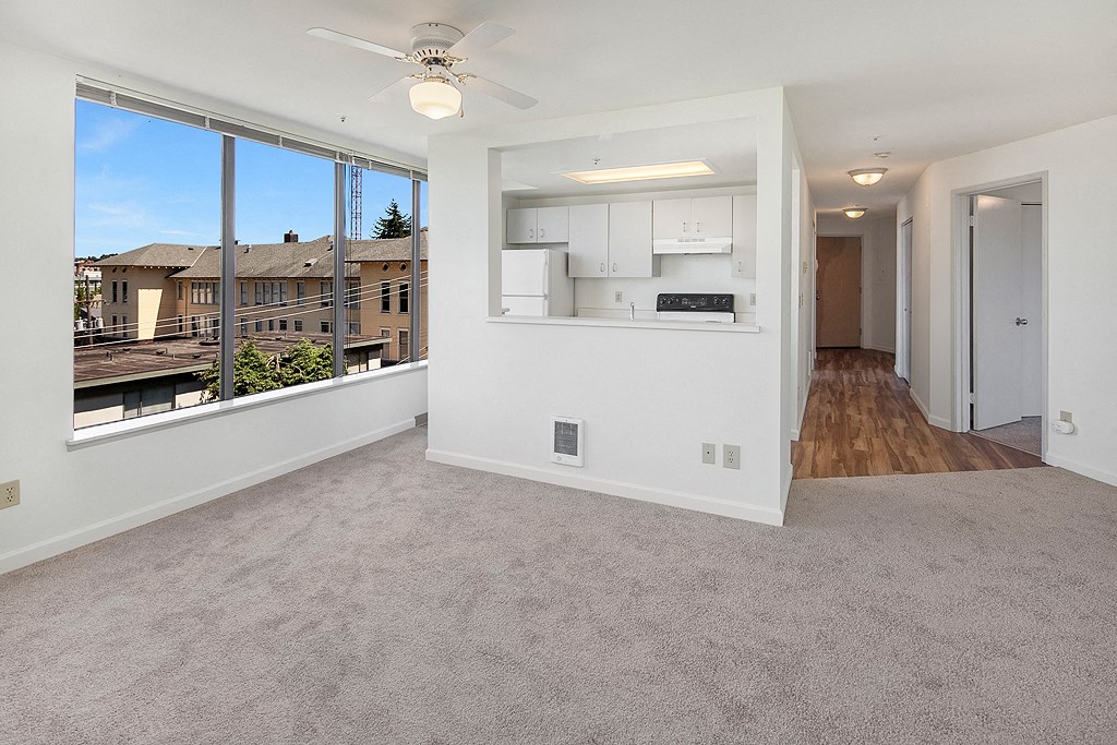 an empty living room with a large window and a kitchen