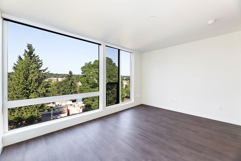 an empty living room with large windows and wood flooring