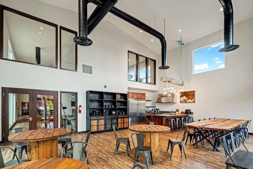 a dining room with tables and chairs and a kitchen in the background