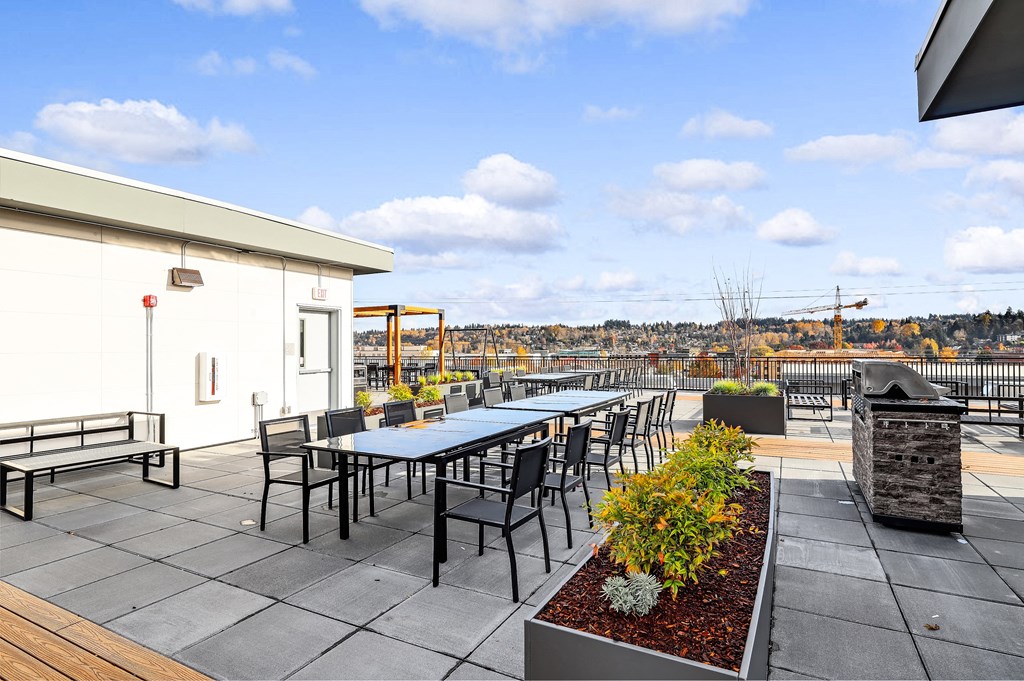 the terrace of the building has tables and chairs and a fire pit