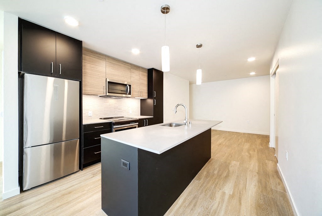 a kitchen with a large island and a stainless steel refrigerator