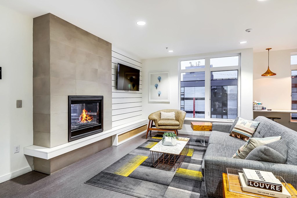 A modern living room with a fireplace and a grey couch.