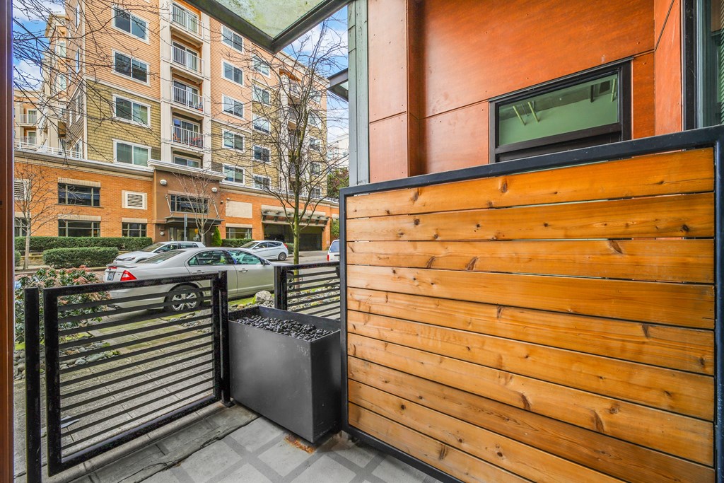 the front door of a condo with a wooden wall and black railing