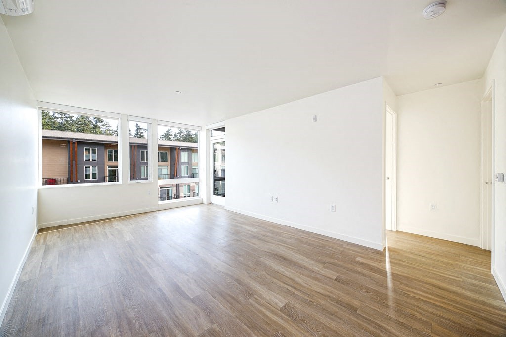 an empty living room with wood floors and a large window