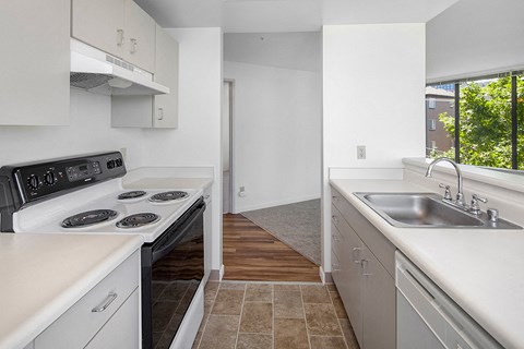 a kitchen with white counters and a sink and a window
