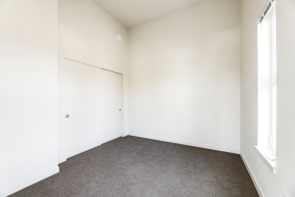 a bedroom with white walls and carpet