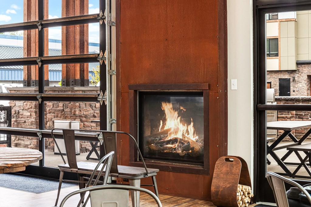 a fireplace and tables and chairs in front of a window