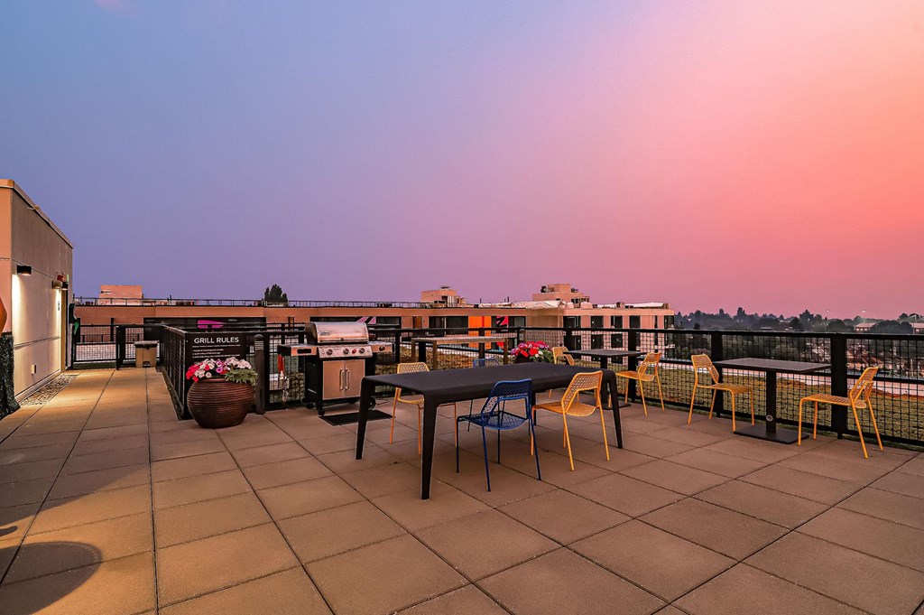 A patio with a table and chairs overlooking a cityscape at dusk.