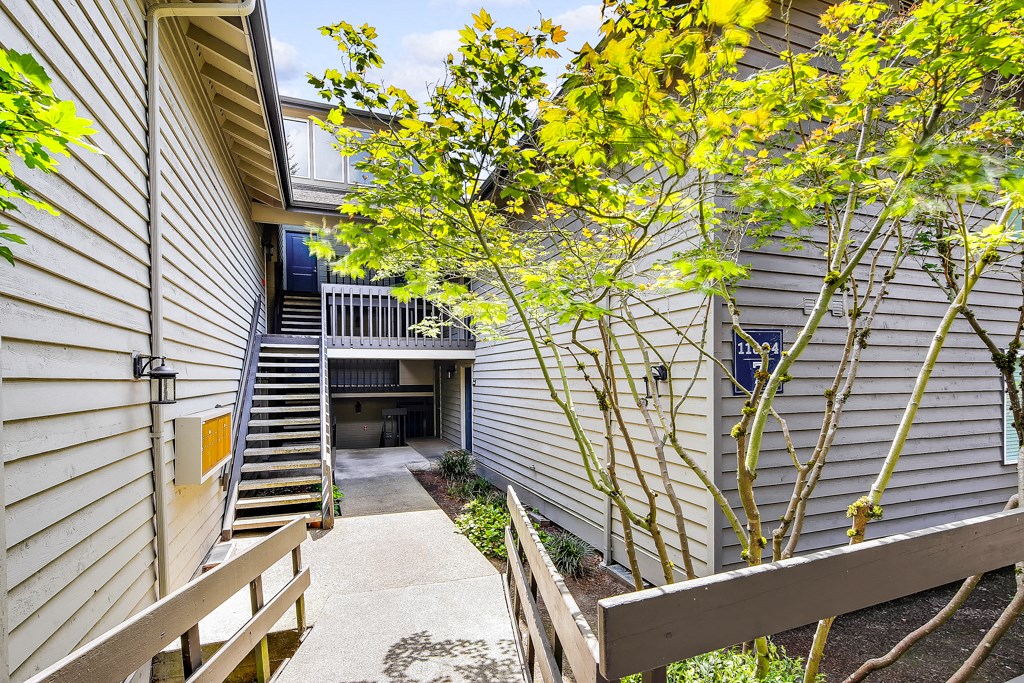 a small courtyard with stairs and trees next to a white house