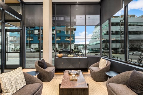 a lounge area with chairs and a coffee table and large windows