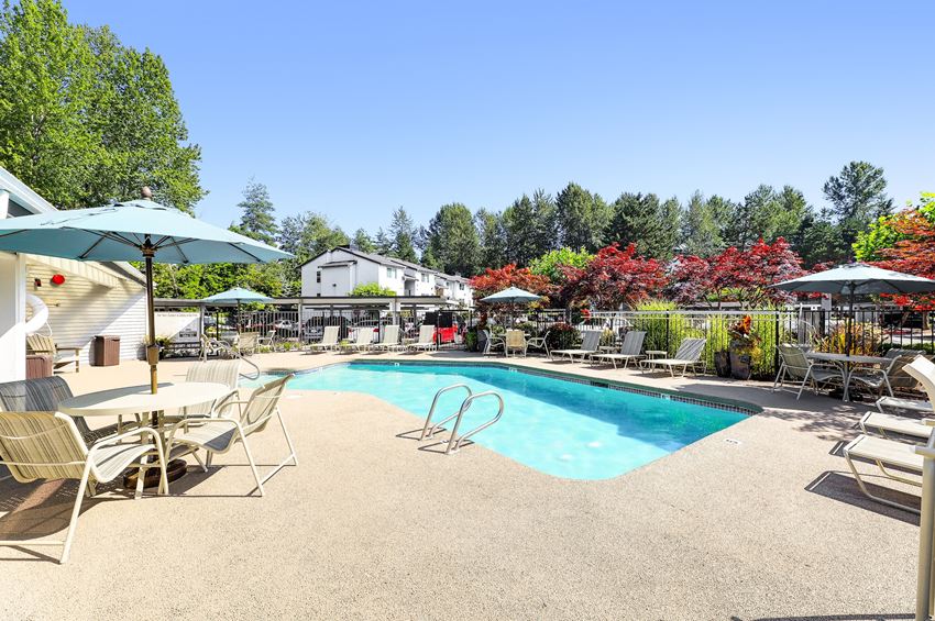 a swimming pool with chairs and umbrellas next to a resort style pool