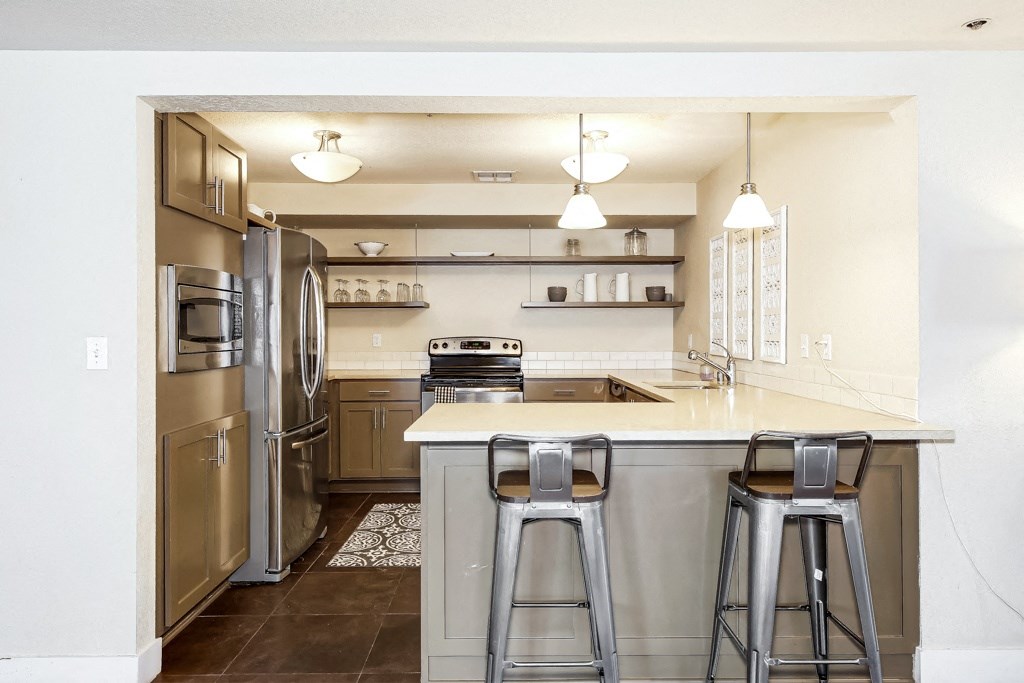 a kitchen with stainless steel appliances and a bar with three stools