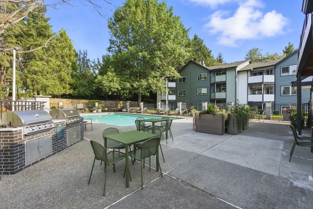 A patio with a table and chairs and a grill.