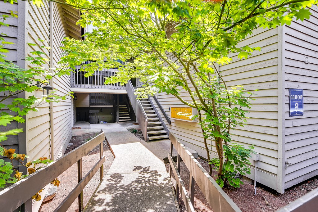 a pathway between two buildings with stairs and a tree