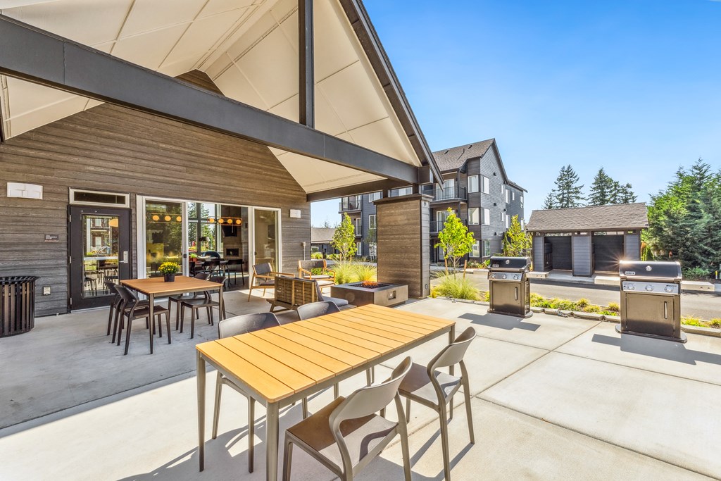 a patio with tables and chairs and a grill