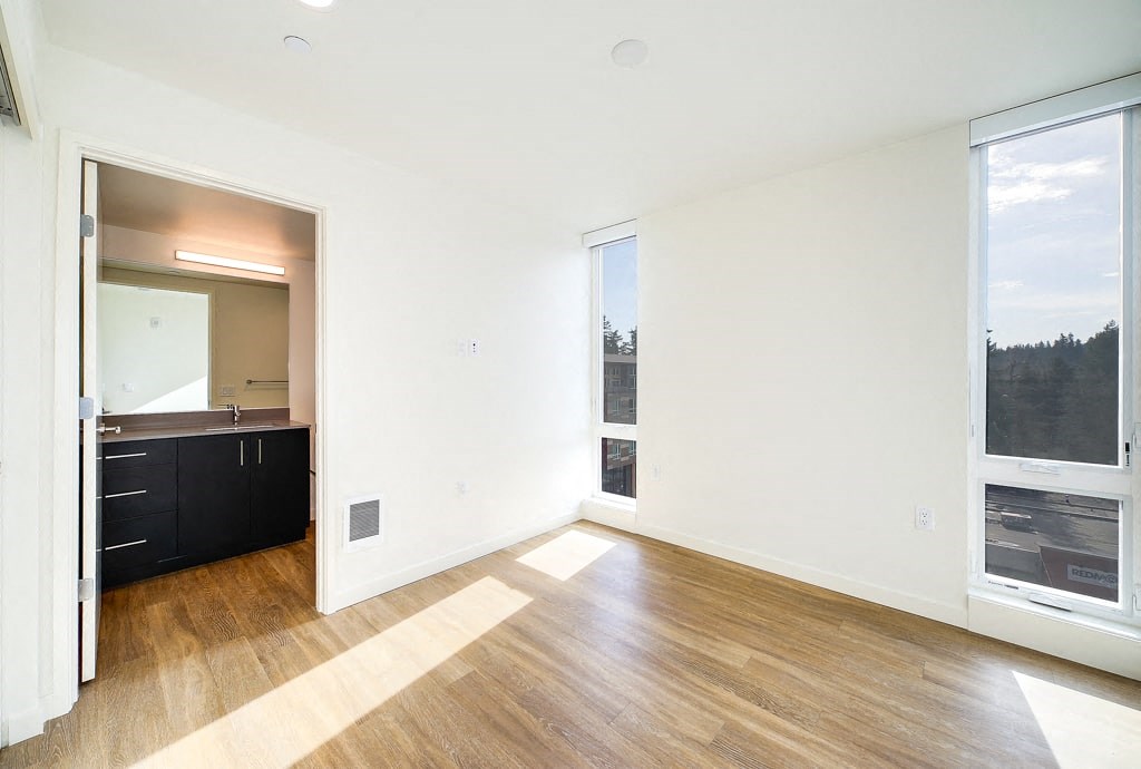 an empty living room with wood floors and a large window