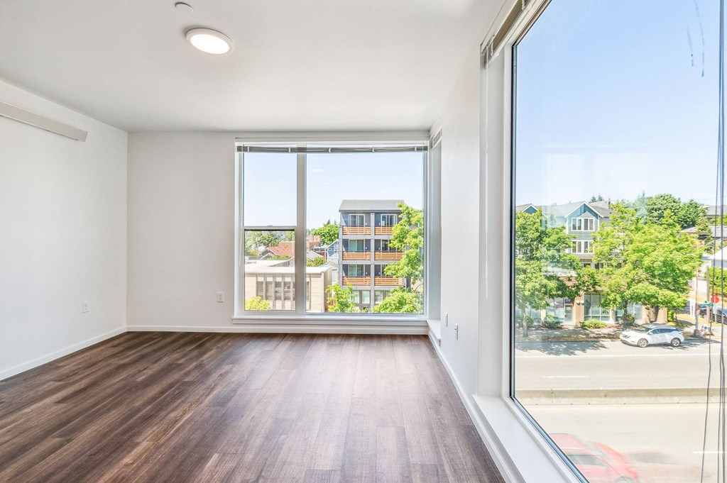 a bedroom with a large window and hardwood floors