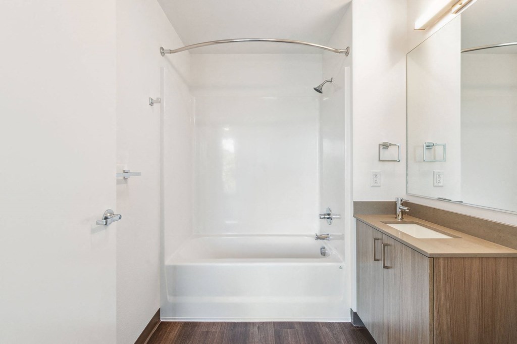 a bathroom with white walls and a wooden floor