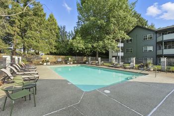 A swimming pool surrounded by chairs and trees.