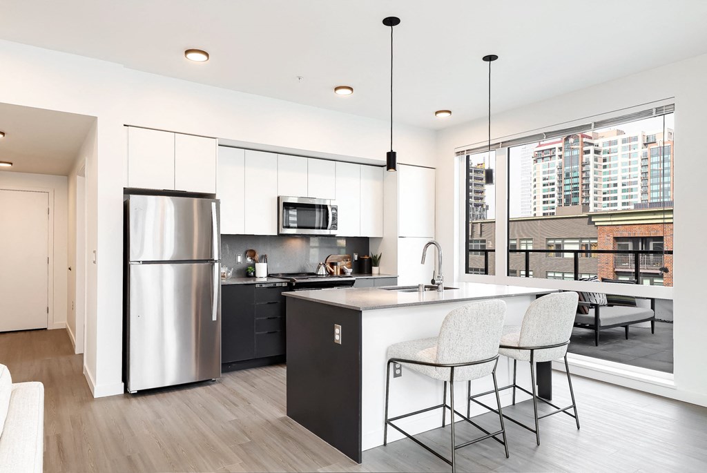 a kitchen with a large island and a stainless steel refrigerator