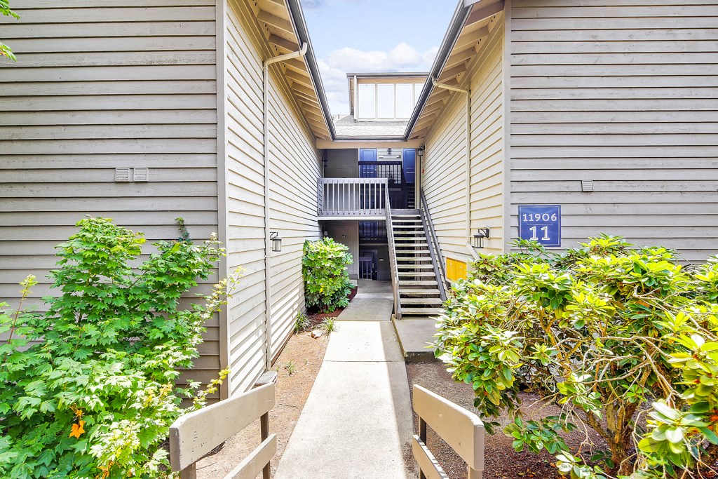 a walkway between two buildings with plants and a staircase
