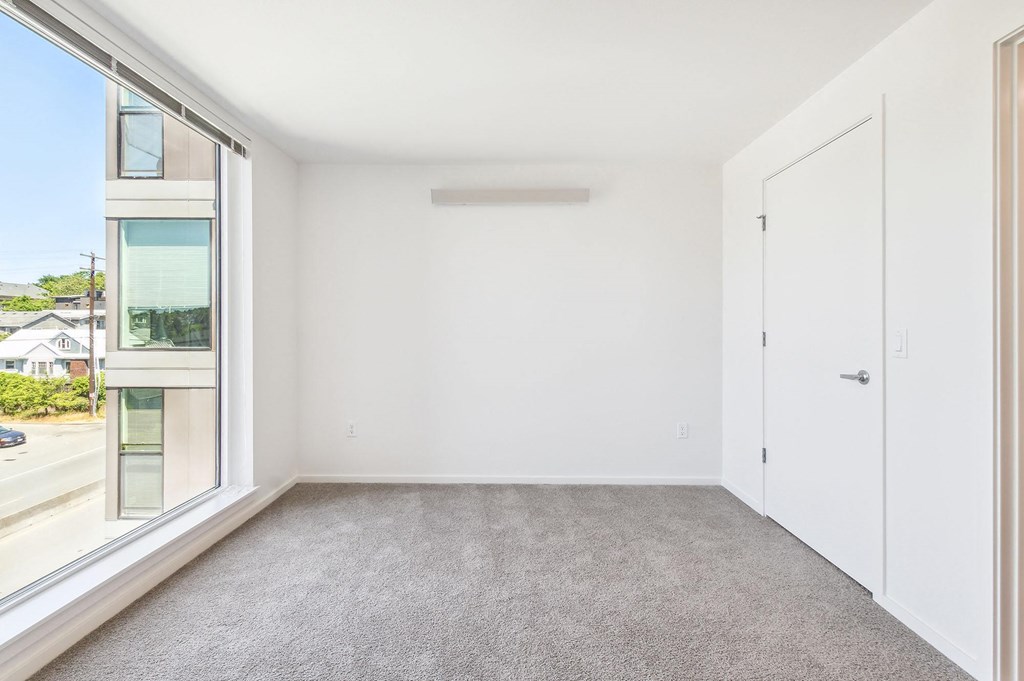 a bedroom with a large window and white walls