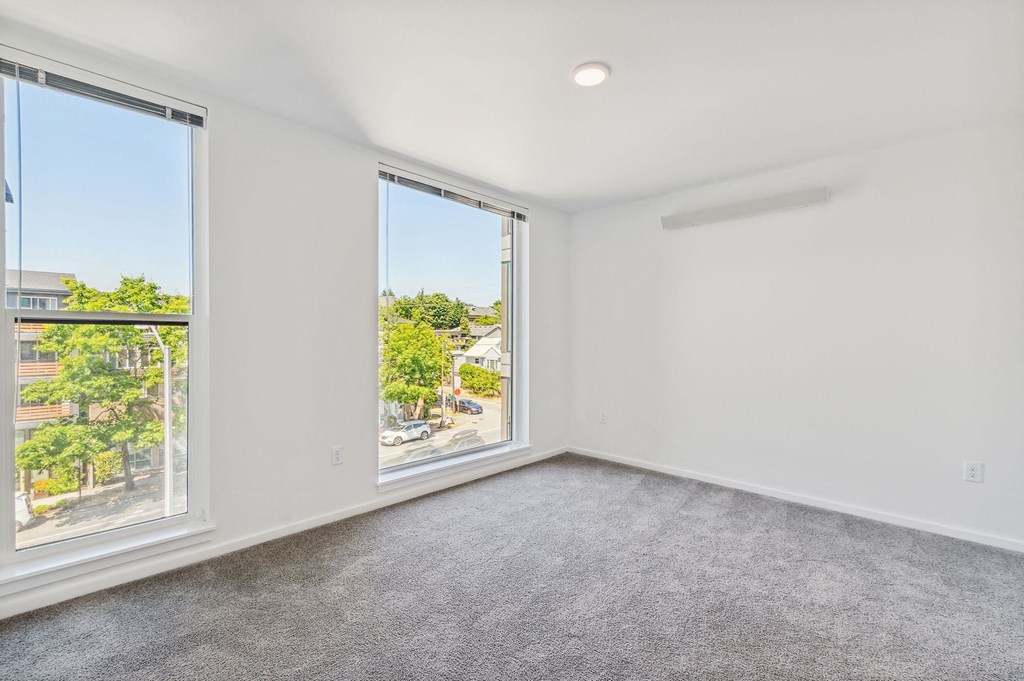 a bedroom with a large window and a carpeted floor