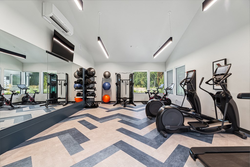 a gym with weights and cardio equipment in a building with windows