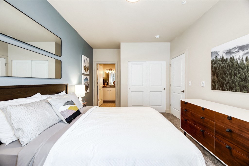 a bedroom with a bed and a dresser and a bathroom