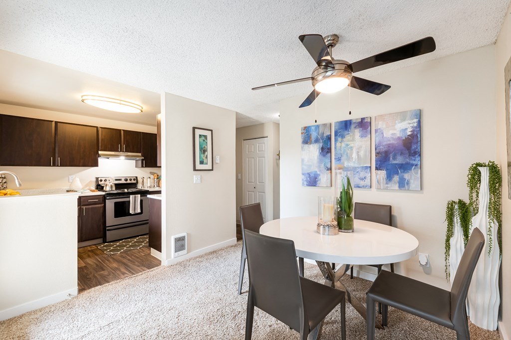 a dining area with a table and chairs and a ceiling fan