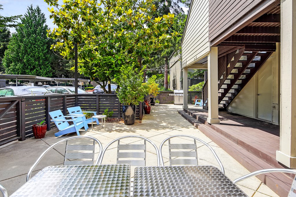 a patio with metal tables and chairs and a blue bench
