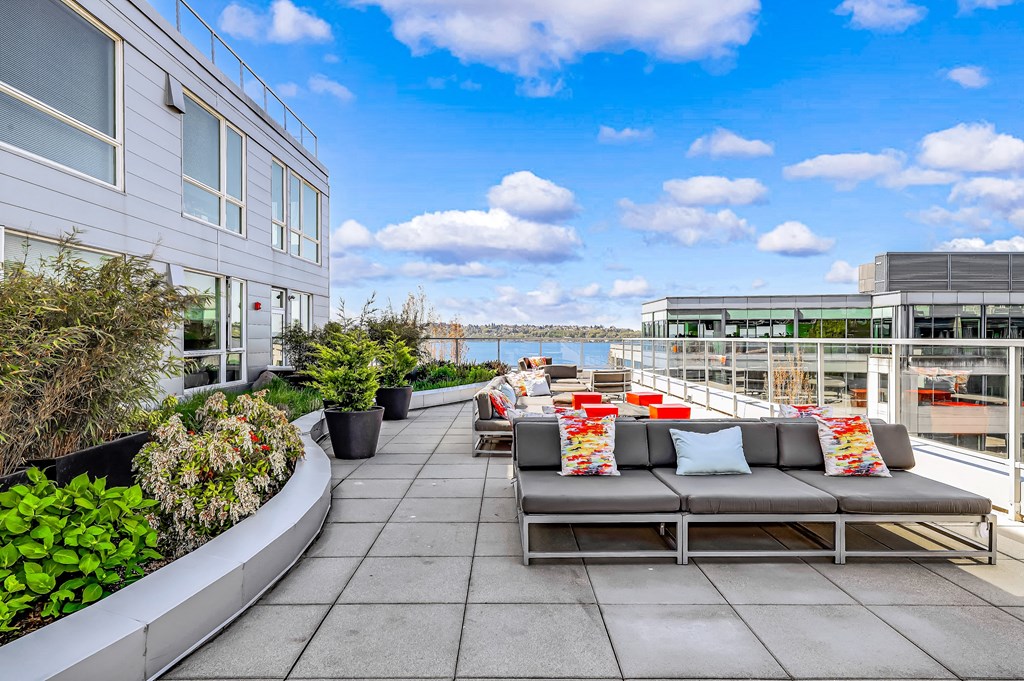 a seating area on the roof of a building with a view of the water