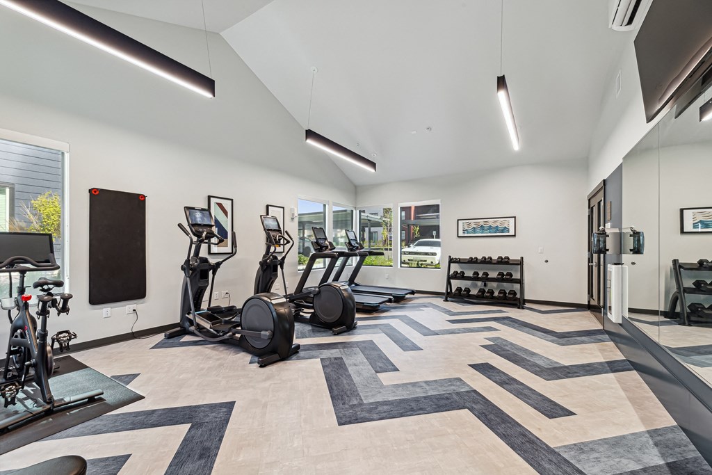 a gym with treadmills and other exercise equipment in a building with windows