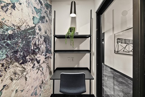 a desk with a plant and a chair in a room with a white wall