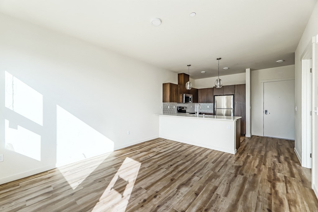 a kitchen and living room with hardwood floors and white walls