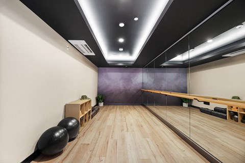 a squash court with a wooden floor and a purple wall and a table with balls