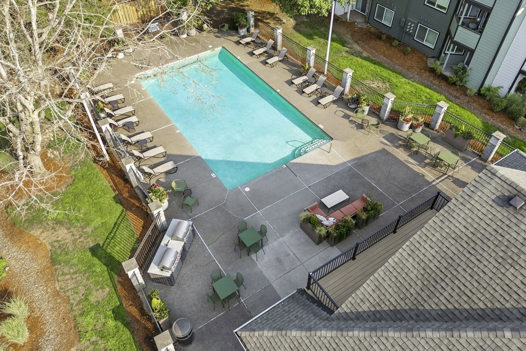 An aerial view of a pool surrounded by lounge chairs and umbrellas.