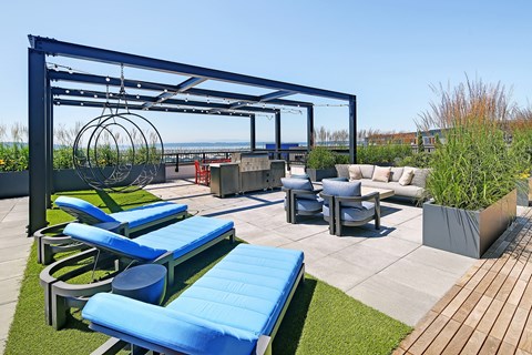 a rooftop patio with lounge chairs and tables and a pergola