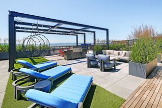 a rooftop patio with lounge chairs and tables and a pergola