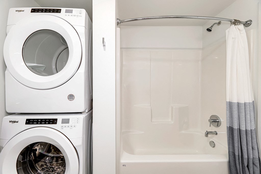 a washer and dryer in a bathroom next to a shower and a tub
