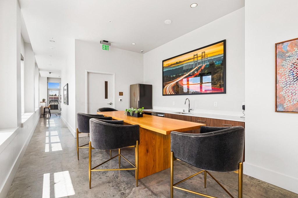 a room with a long wooden table with four chairs and a large painting on the wall