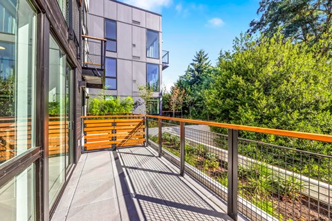 a balcony with a wooden railing and a glass building with trees