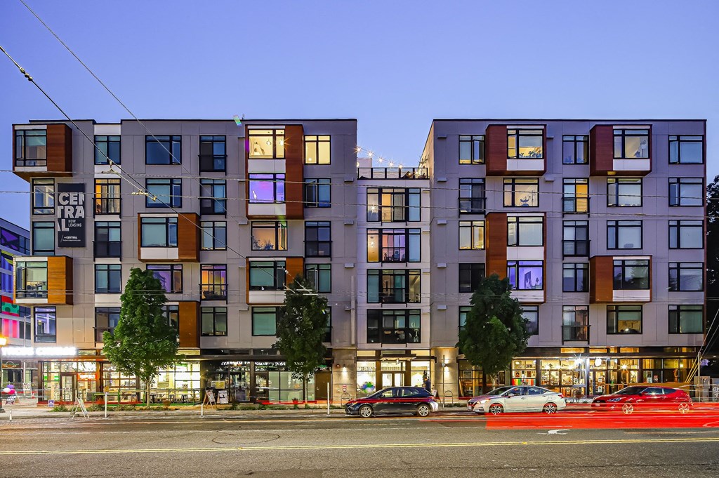 A modern apartment building with a red car parked in front.