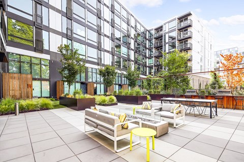 an outdoor patio with chairs and tables in front of tall buildings