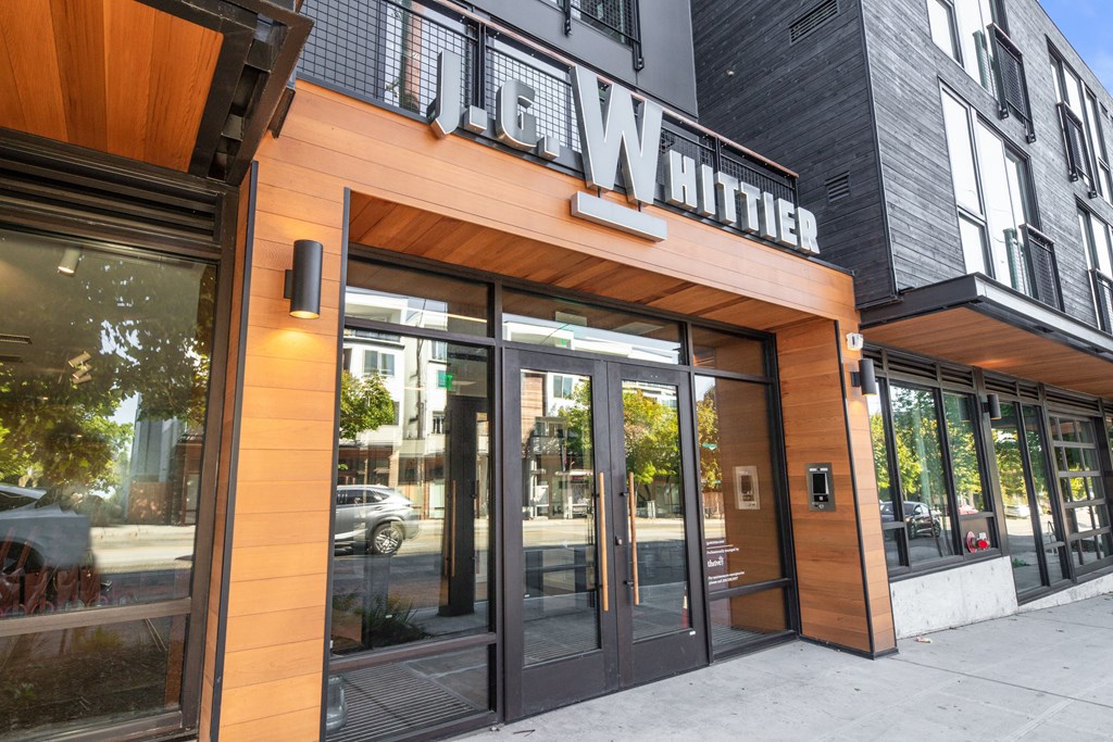 the front of a building with glass doors and a sign on the side of it
