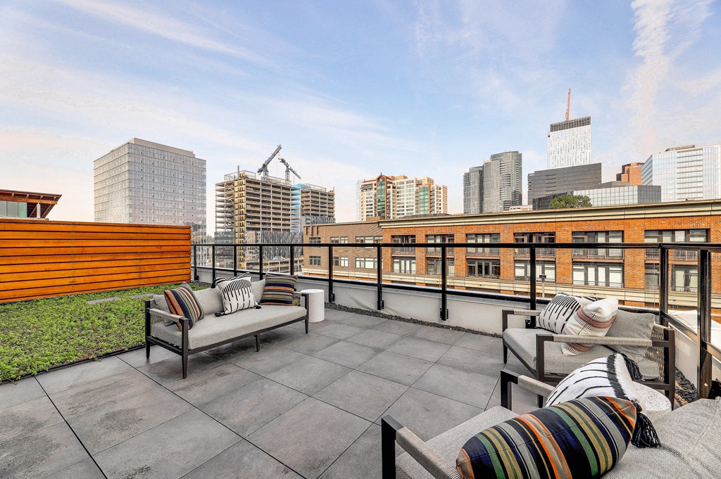 a rooftop patio with chairs and a view of the city