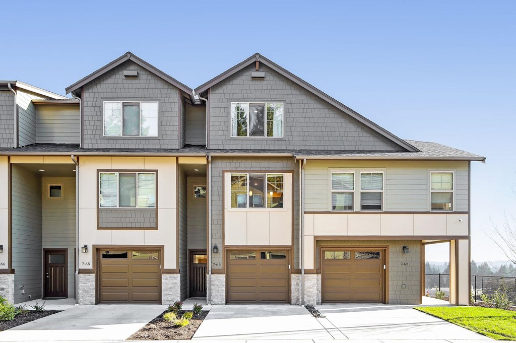 a tan house with brown garage doors