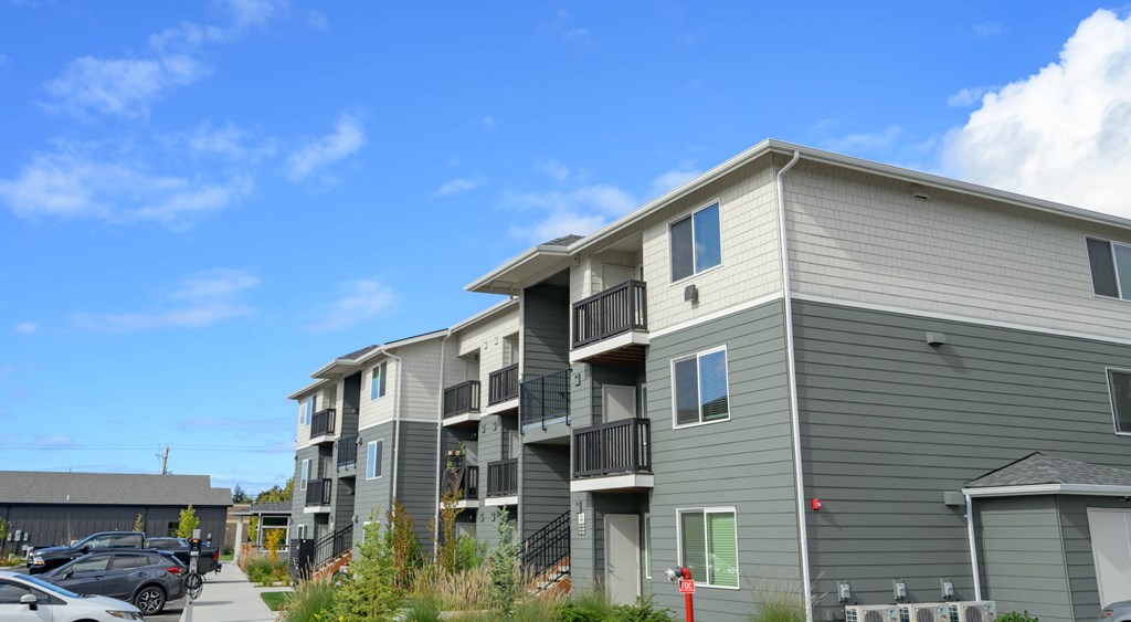 A grey apartment building with a clear blue sky above it.
