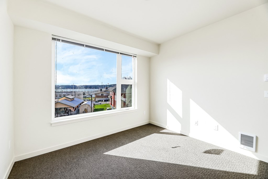 a bedroom with a large window and a carpeted floor